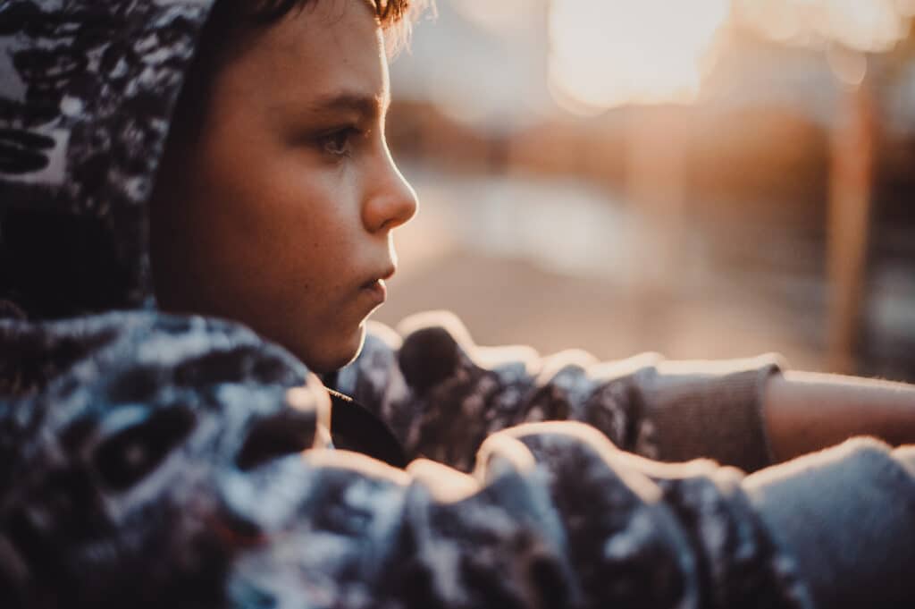 young boy with hood up looking out into the distance