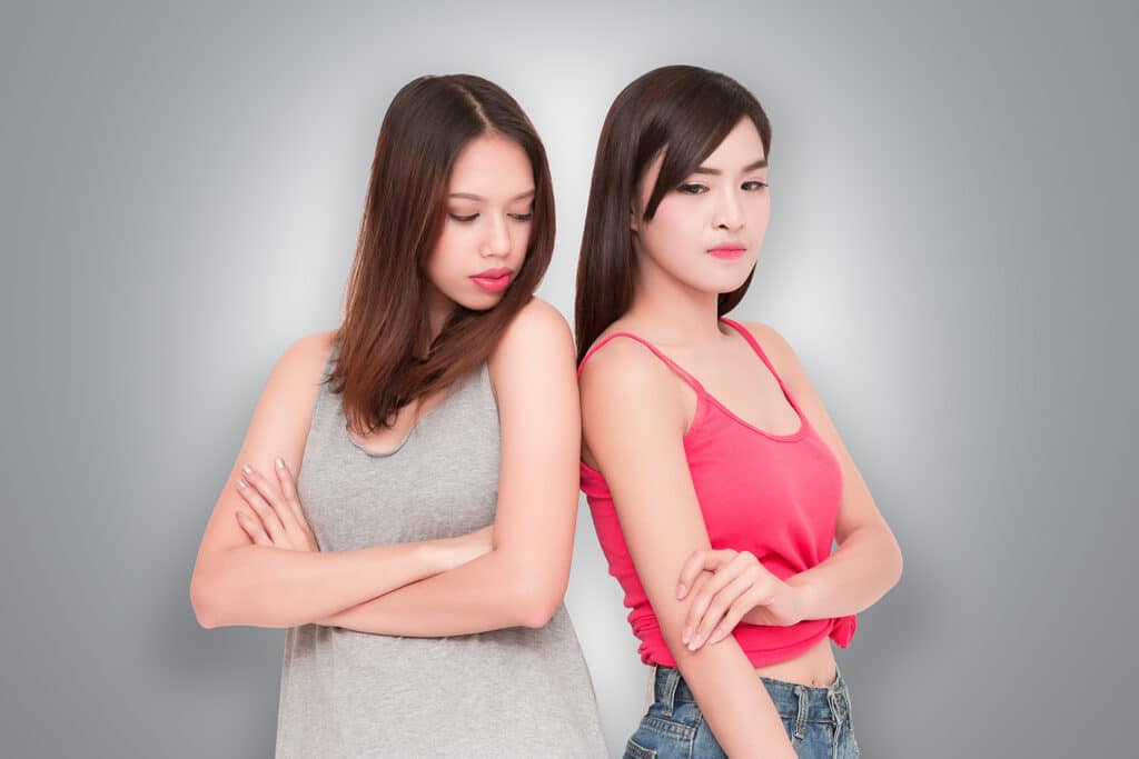 two young women back to back feeling insecure