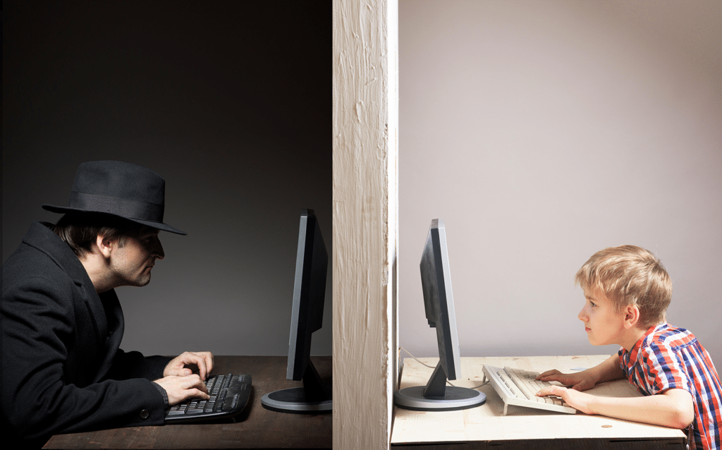 small boy on computer with shady man on computer on other side of wall