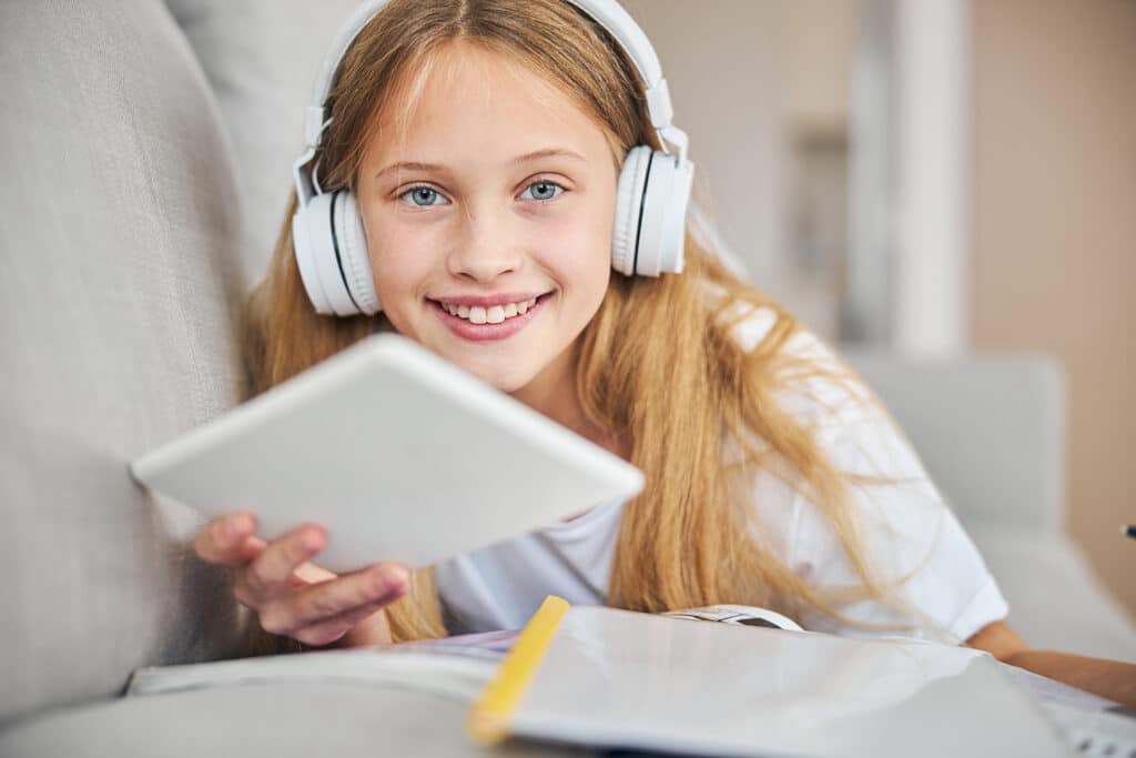 smiling teen girl looking at ipad with headphones on