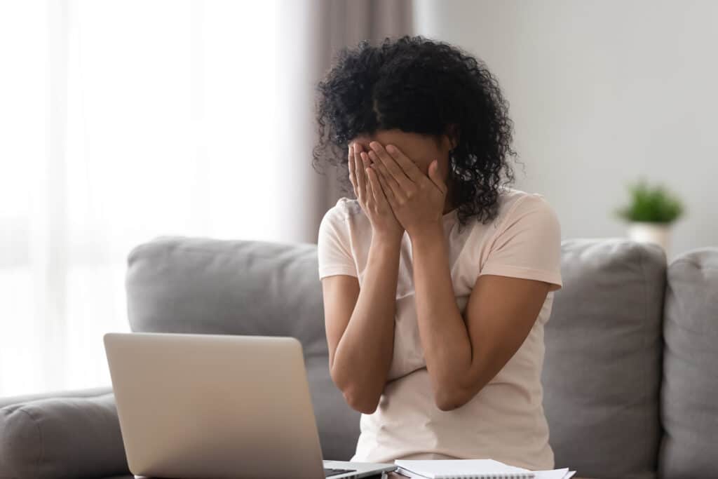 girl covering her face with her laptop open