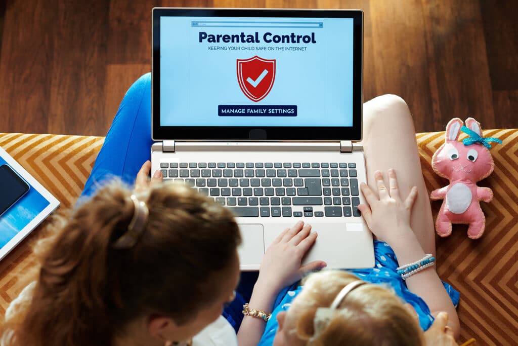 mom and daughter looking at parental controls on laptop