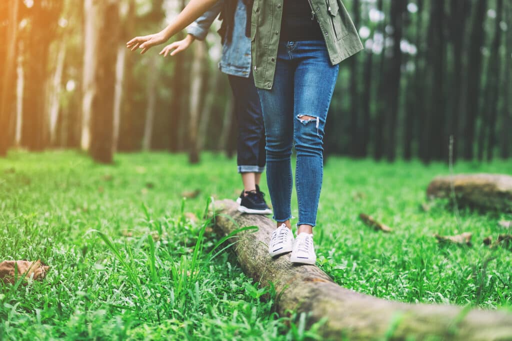 two people balancing on a log