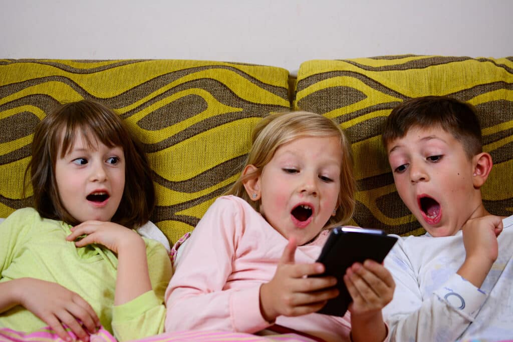 three shocked kids looking at a phone