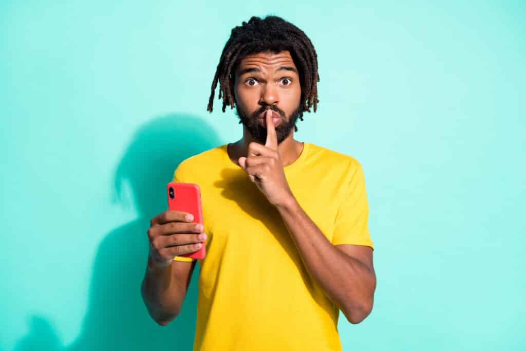man holding phone and pointer finger over his mouth
