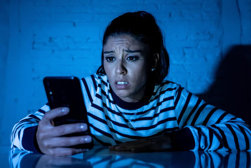 distraught girl looking at phone in dark room