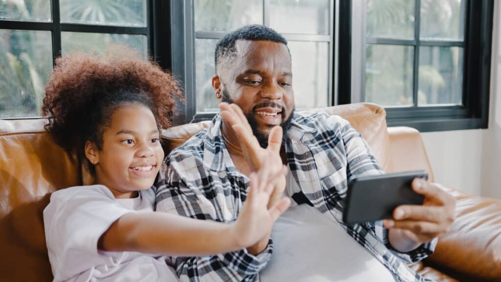 happy father and daughter waving at video call on cellphone