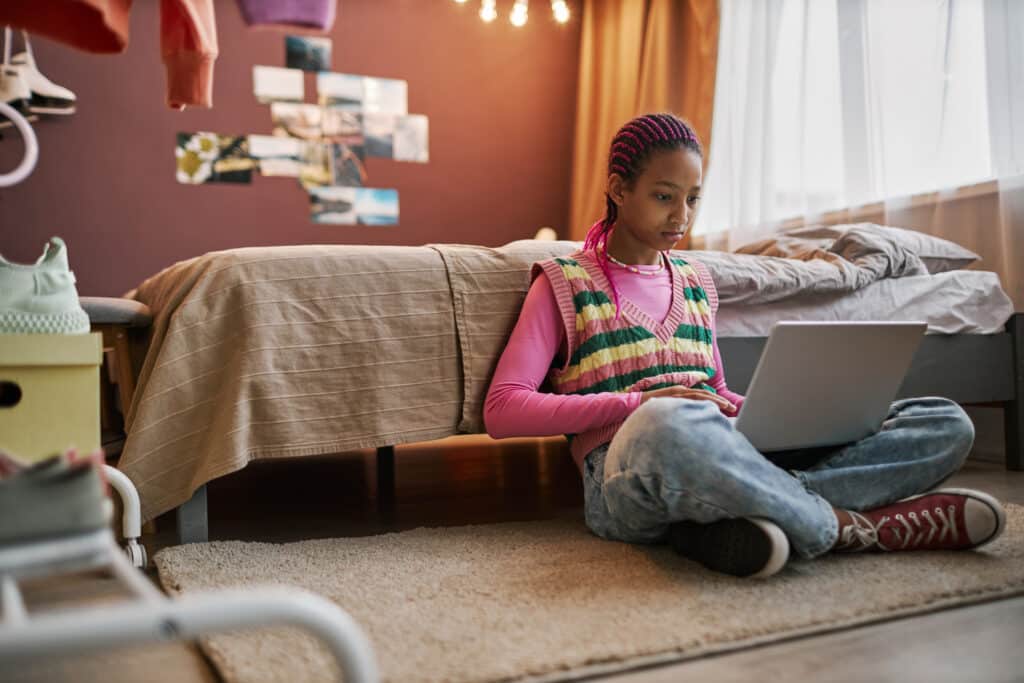 teen girl on laptop on floor of her bedroom